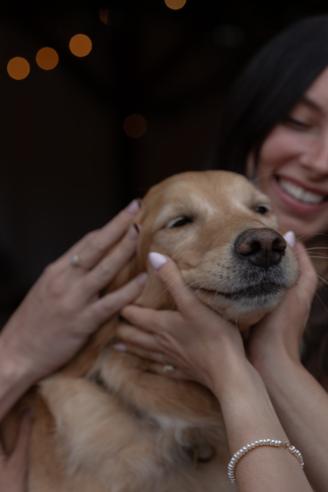 Close-up of a relaxed golden retriever being cuddled by a smiling wedding guest.