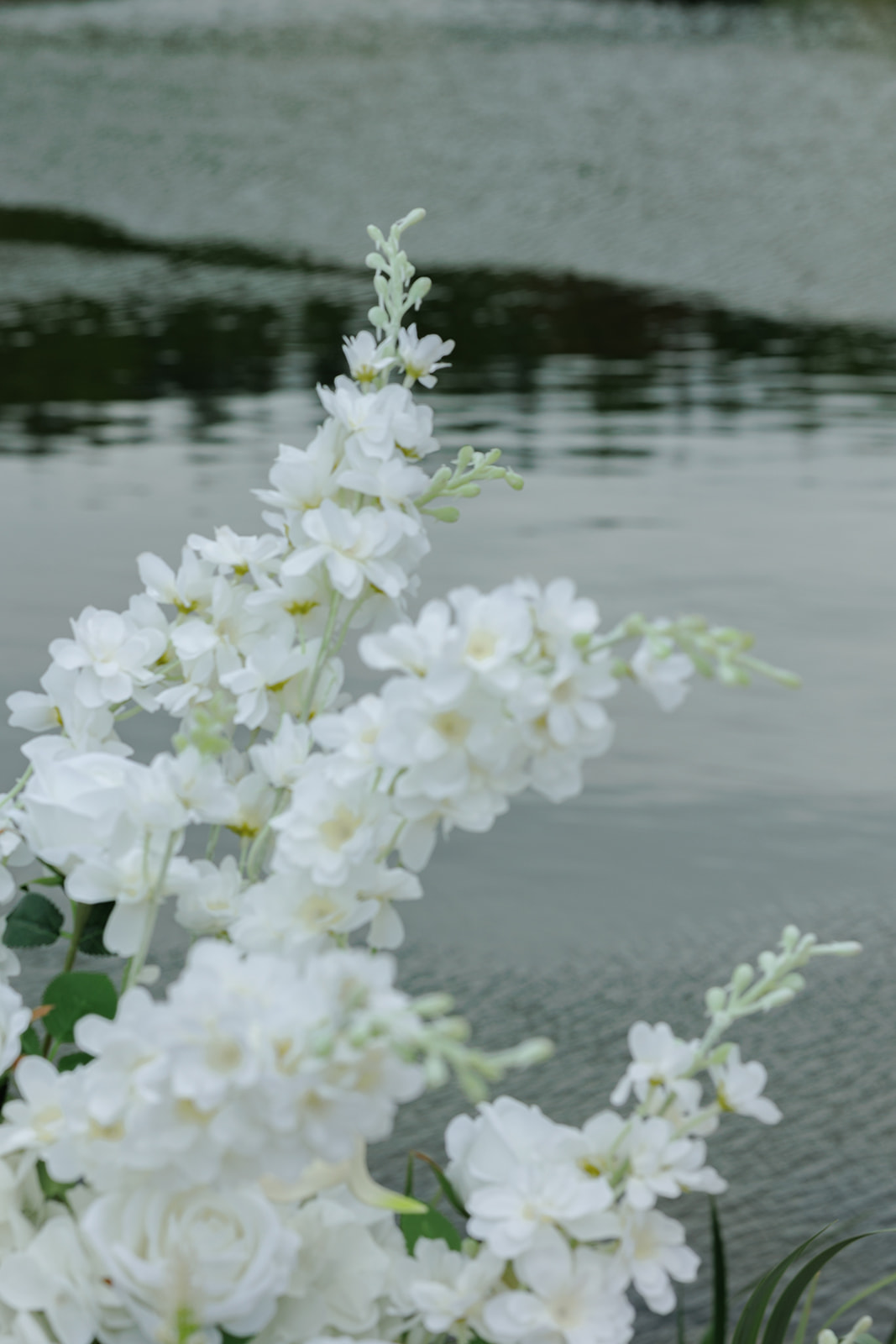 Close-up of white wedding flowers arranged beside the pond.