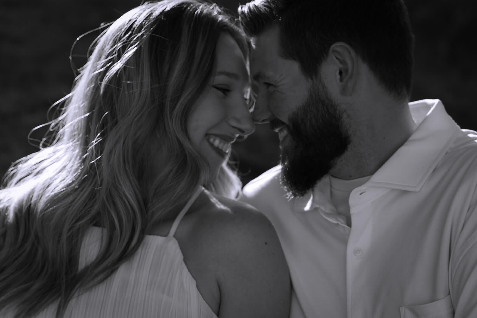 Black-and-white close-up of a couple smiling with their foreheads and noses touching at Beech Hill Barn.