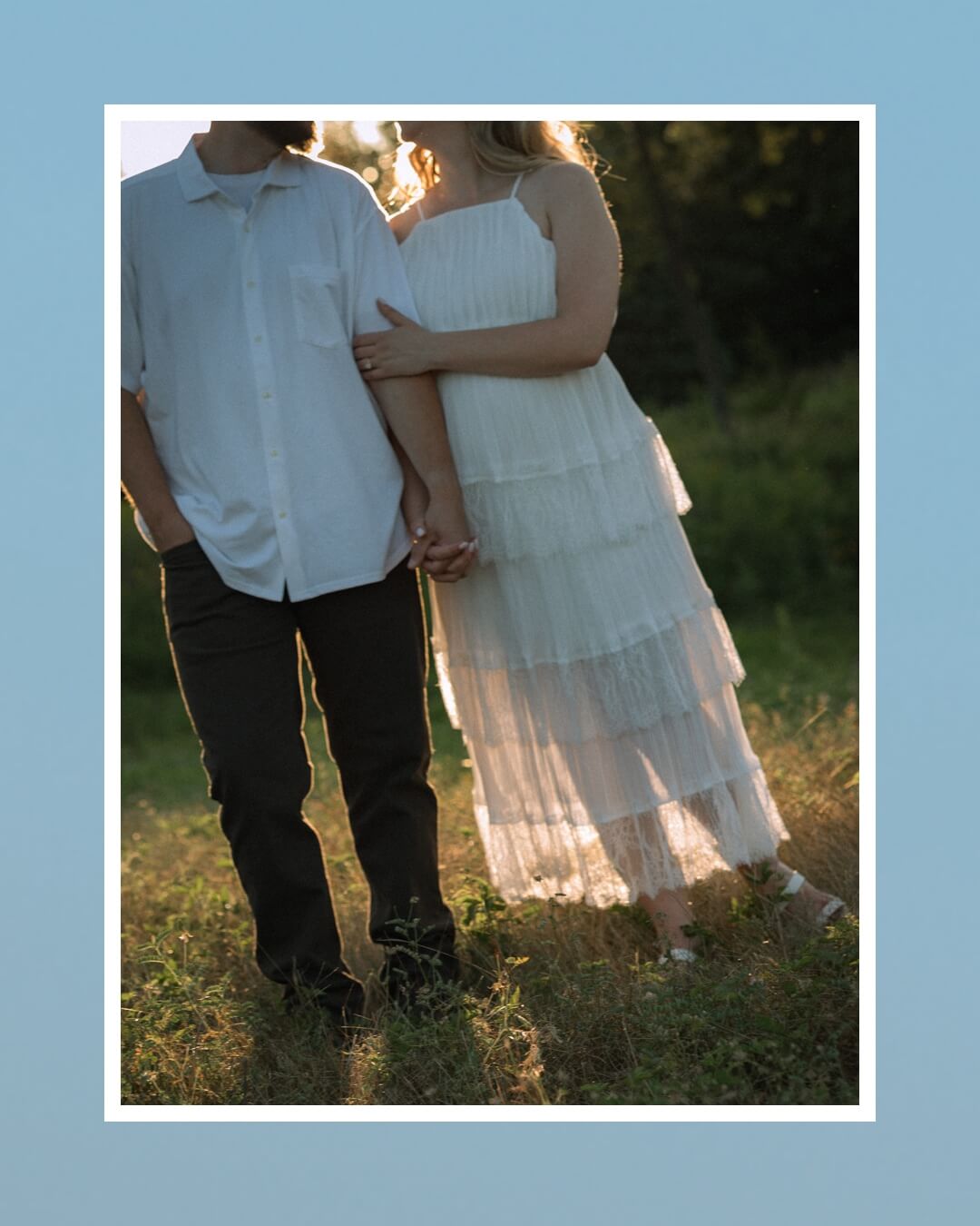 Cropped photograph of a couple standing side by side and holding hands in a sunlit field.